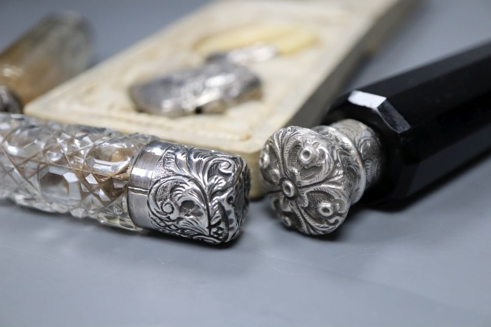 Three assorted white metal topped glass scent bottles including one silver and a childs white metal and ivory teether.